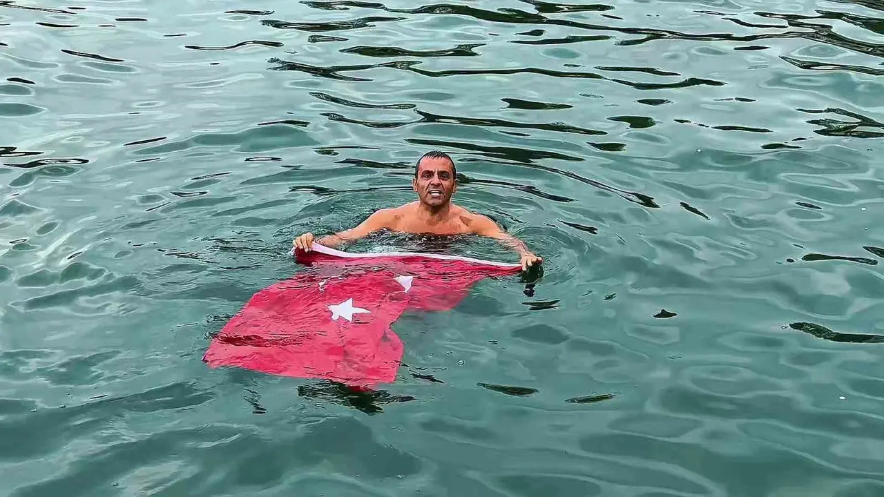 Soğuk ve yağışlı havaya aldırmadı, Türk bayrağıyla denize girdi
