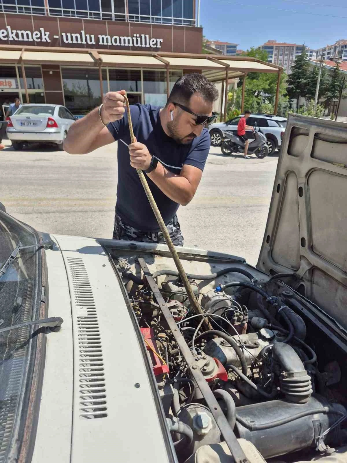 Aracın motoruna giren yılanı elindeki sopayla çıkardı
