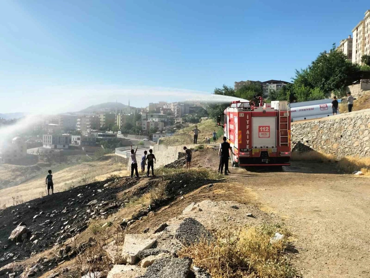 İtfaiyeciler yangın söndürme derdinde, çocuklar serinlemenin keyfinde

