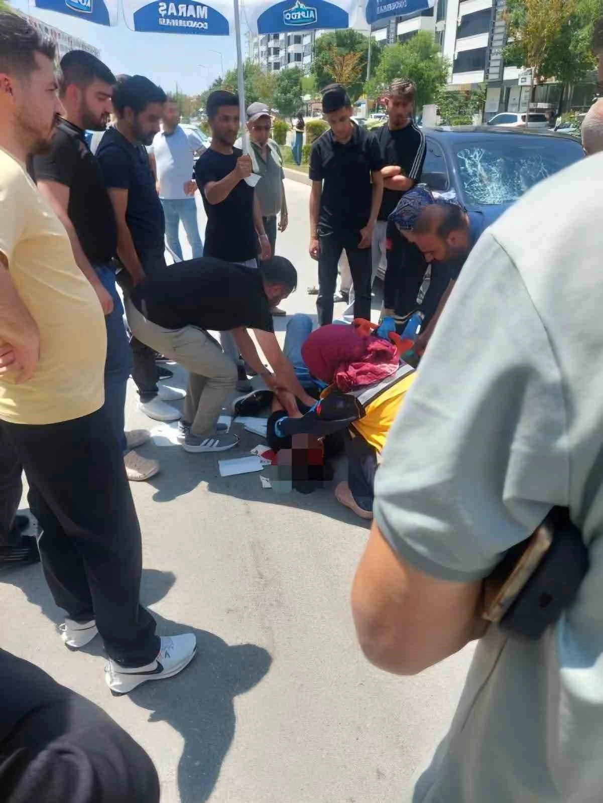 Vatandaşlar yerdeki yaralıyı güneşten korumak için dondurma şemsiyesi kullandı
