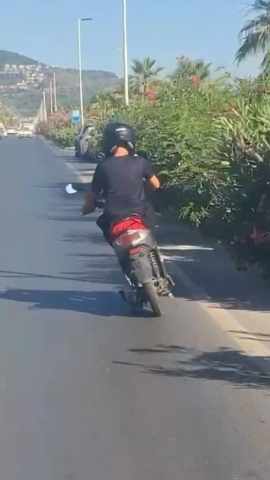 Alanya&rsquo;da motosiklet &uuml;zerinde ayakta ilerleyen s&uuml;r&uuml;c&uuml;n&uuml;n tehlikeli yolculuğu kamerada
