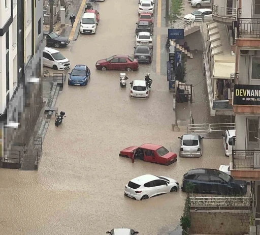 Yağmurda mahsur kalan motosikletli &ccedil;areyi otomobilin &uuml;zerine &ccedil;ıkmakta buldu
